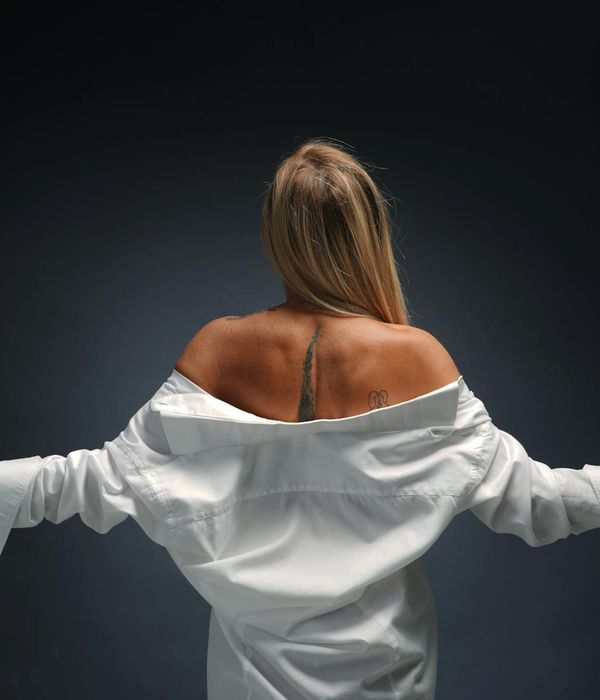 Woman in a peaceful yoga pose against a dark background with turquoise light.